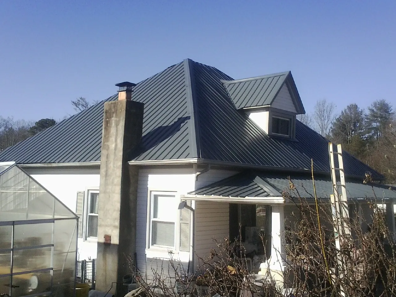 Dark blue standing seam metal roof on a white farmhouse with dormer — Slate & Tile Roof Repair by Roofing Brothers in Garwin