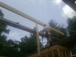 Carpenter setting a ridge beam over a new addition frame — Ice Dam Removal by Roofing Brothers in Garwin