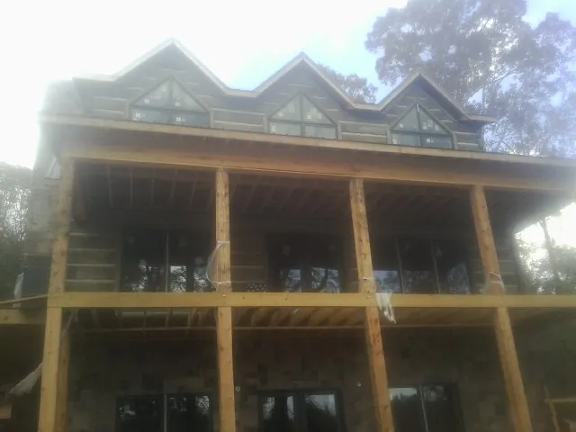 Dormers and porch framing on a large log home under construction — Roof Coating work by our crew in Garwin