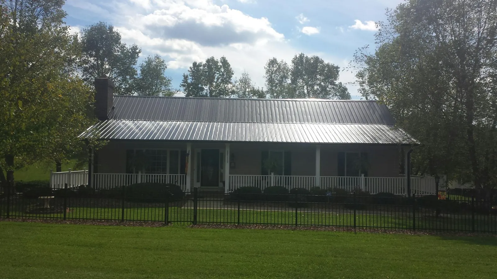 Gray metal roof on a brick ranch with a full width front porch — Gutter Guard Installation work by our crew in Garwin
