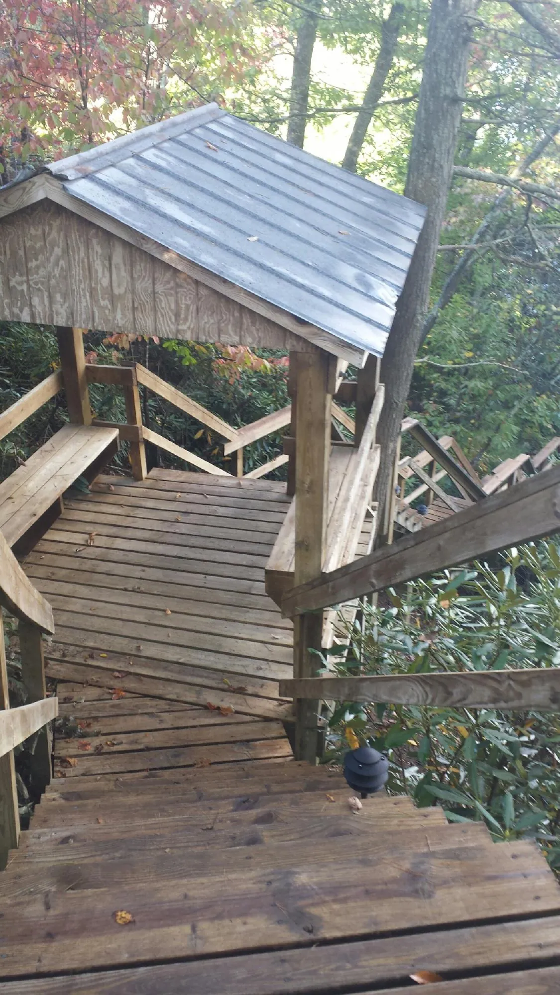 Metal roofed shelter over wooden steps on a wooded walkway — Skylight Repair & Installation work by our crew in Garwin