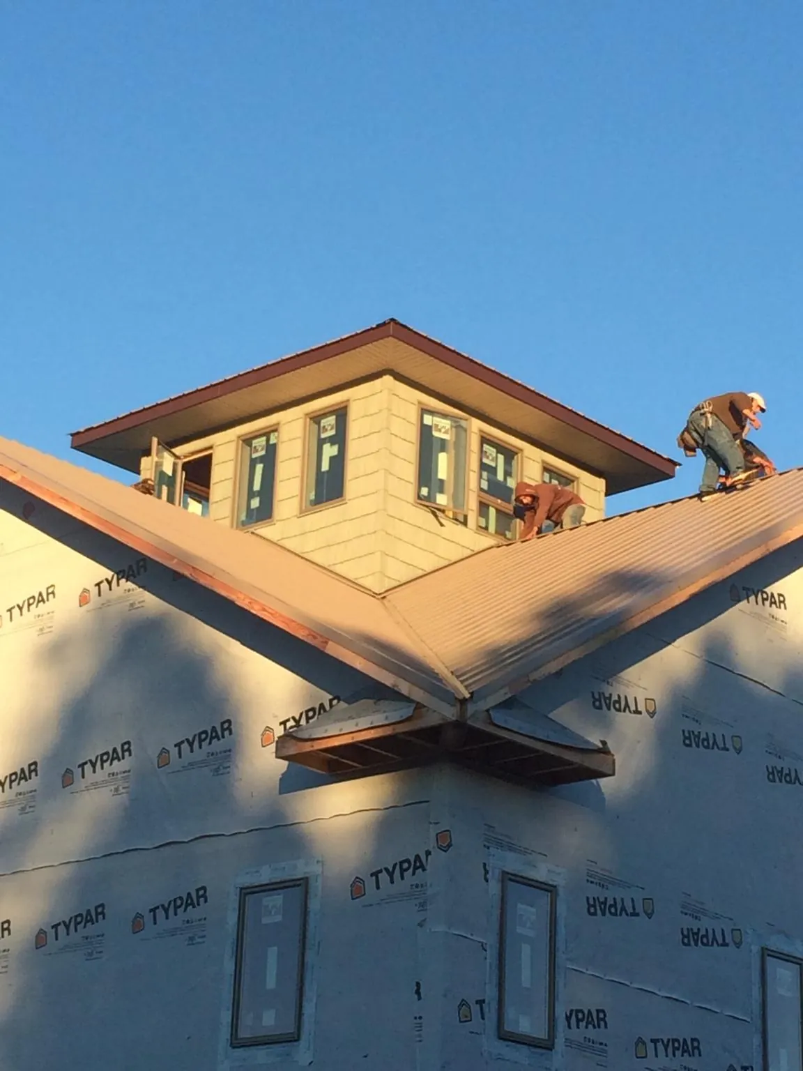 Roofers working around a rooftop cupola on a new metal roof at sunset — Roof Waterproofing in Garwin by Roofing Brothers
